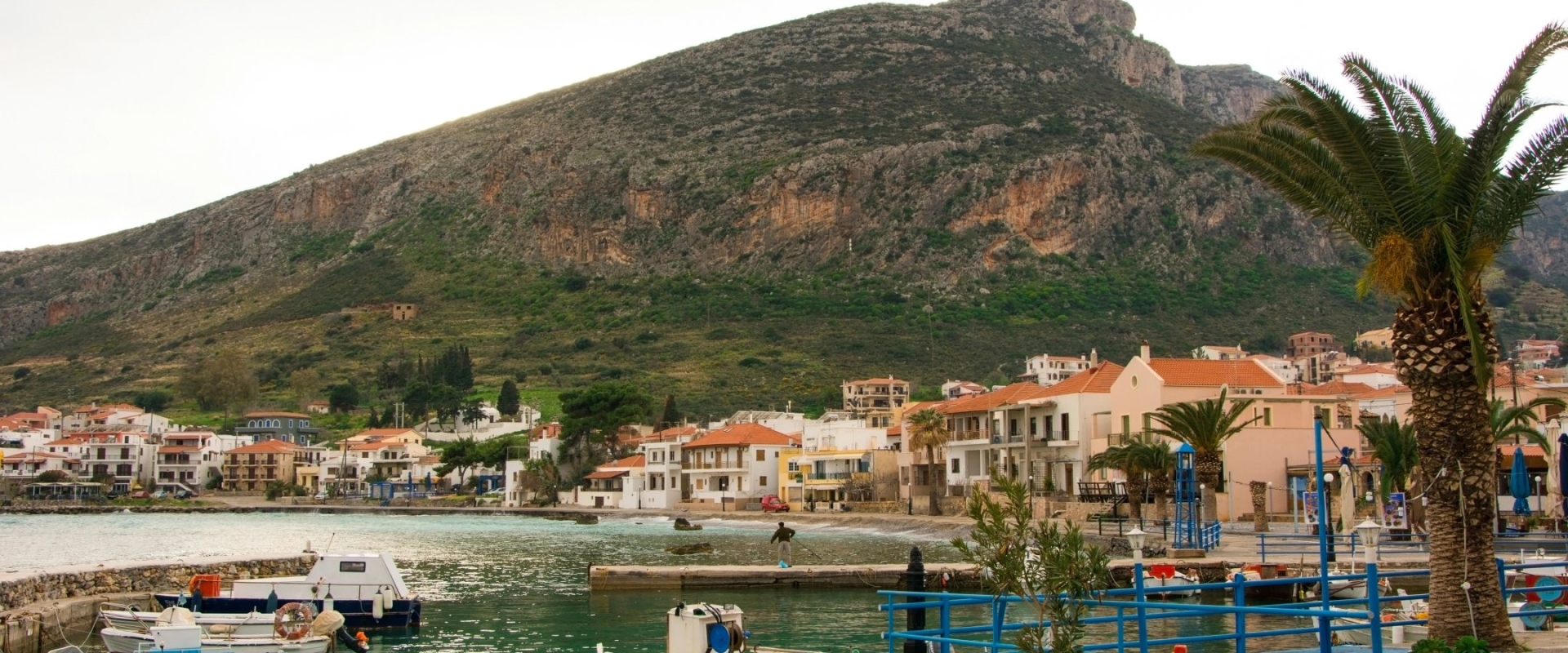 A view of the imposing fortified rock of Monemvasia rising dramatically from the sea, with the red-tiled roofs of the medieval town clinging to its hidden side.